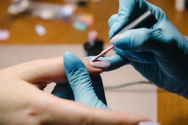 Маникюрша делает аппаратный маникюр крупным планом. Лечение ногтей с помощью аппаратного маникюра — стоковое фото