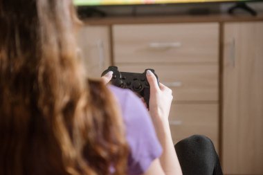 Oyun oynayan mutlu bir kadın, elinde joystick ile yatakta oturuyor..