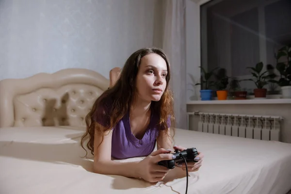 Dziewczyna gracz gra z gamepad patrząc na ekranie przed nią. — Zdjęcie stockowe