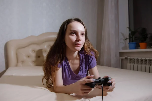 女の子のゲーマーは、彼女の前の画面を見ながら、ゲームパッドで再生されます. — ストック写真