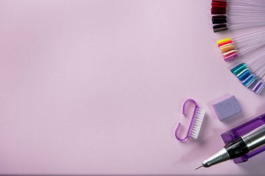 Pembe arka planda manikür ve pedikür ekipmanlarının üst görüntüsü