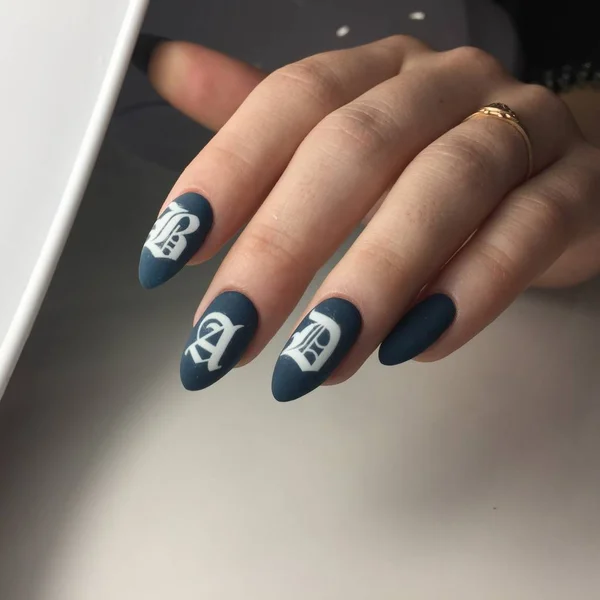 Mujer con manicura de color carne con diseño y la inscripción MALO, de cerca — Foto de Stock