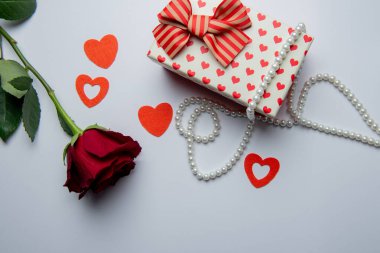 Kırmızı kalpli hediye kutusu ve beyaz arka planda gül.