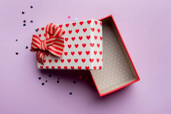 Caixa de presente com bela fita vermelha em um fundo rosa — Fotografia de Stock