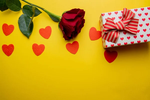 Pudełko z czerwonymi sercami i różą na żółtym tle — Zdjęcie stockowe