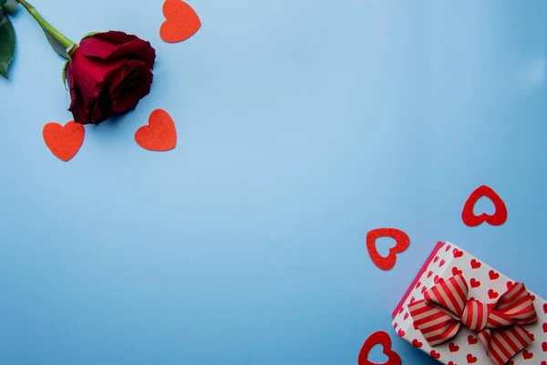 Pudełko z czerwonymi sercami i róża na niebieskim tle — Zdjęcie stockowe
