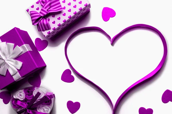 Corazón hecho de cinta púrpura brillante con cajas de regalo sobre un fondo blanco. Espacio libre para espacio de copia — Foto de Stock