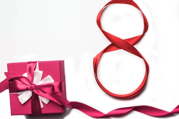 8 de marzo Día de la Mujer concepto. Número 8 de cinta roja y caja de regalo rosa sobre fondo blanco, aislado. — Foto de Stock