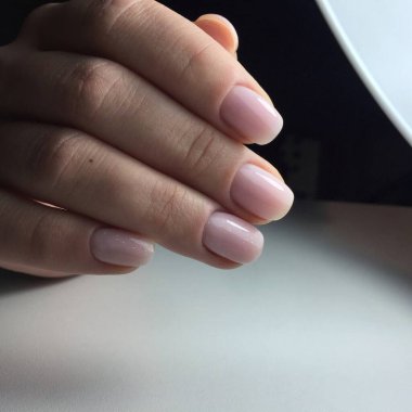 Tırnaklarında pembe manikür olan bir kadının elleri. Manikür güzellik salonu konsepti. Metin veya logo için boş yer.