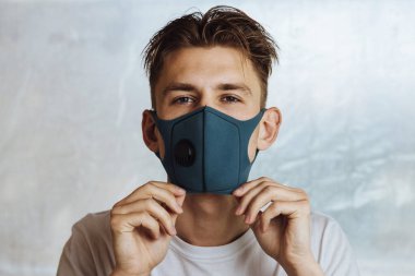 Genç adam, Coronavirus gibi bulaşıcı hastalıklara karşı korunmak için yüzüne tıbbi maske takıyor.
