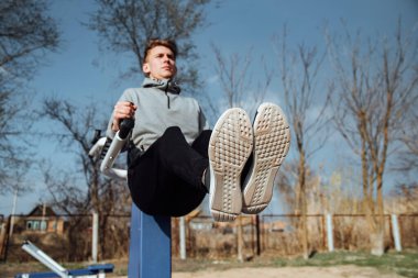 Barlarda mekik çeken genç bir adam. Açık hava barlarında spor yapan bir jimnastikçi..