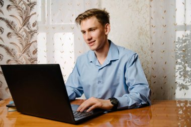 Erkek bir serbest çalışan evdeki bir bilgisayarda çalışıyor. Evde dizüstü bilgisayar kullanan bir iş adamı. İnternet pazarlaması, serbest çalışma, evden çalışma, çevrimiçi öğrenme, öğrenim kavramı.