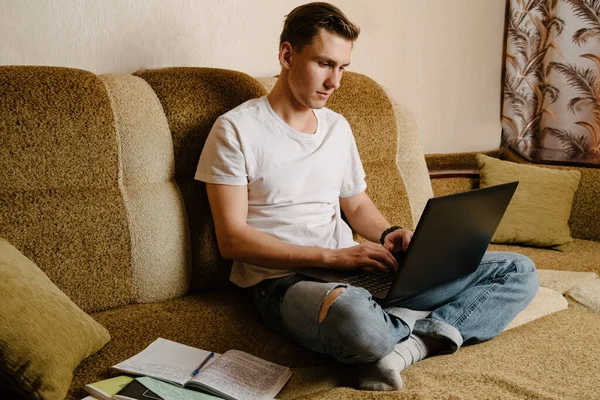 Joven Hace Tarea Cuaderno Trabaja Una Computadora Portátil Sillón Estudiante — Foto de Stock