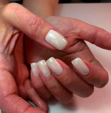 Çivili beyaz manikür. Beyaz manikürlü bir kadın eli.