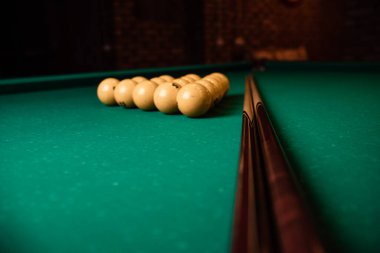 Bilardo sopaları ve yeşil bilardo masasında sarı bilardo topu piramidi. Toplu bilardo masası. Yakın plan.