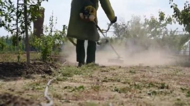 Bir adam çimleri biçme makinesiyle biçiyor. Bir işçi çimleri benzin biçme makinesiyle biçiyor.