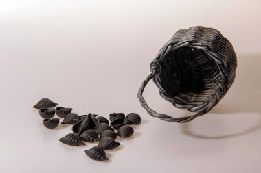 Mürekkepbalıklı çiğ siyah makarna. Kalamar mürekkepli Durum irmikli makarna. Siyah hasır küçük sepet. Kopyala, metin için boşluk.