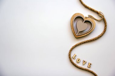 Word love made of wooden letters with a wooden heart hanging on a twine on a white background. Love concept. Valentine's day concept. Top view, flat lay, copy space.