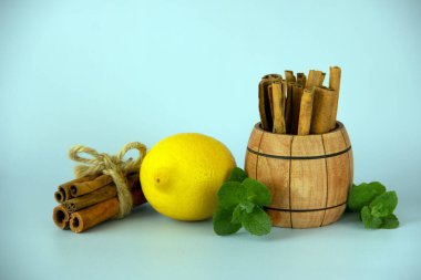 Limon, nane, sicimle bağlanmış tarçın, tarçınlı ahşap bir fıçı. Geleneksel tıbbın soğuğundan bir içecek hazırlamak için gerekli malzemeler. Mavi arkaplanda izole.