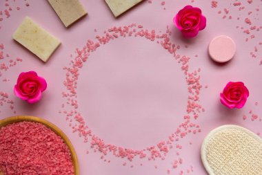 Ahşap tabakta pembe banyo tuzu, doğal sabun, duş süngeri, güller, pembe arka planda banyo bombası. Vücut bakımı konsepti, organik banyo ürünleri. Spa kozmetik. Düz yatıyordu. Boşluğu kopyala.