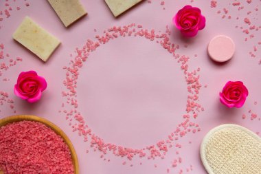 Ahşap tabakta pembe banyo tuzu, doğal sabun, duş süngeri, güller, pembe arka planda banyo bombası. Vücut bakımı konsepti, organik banyo ürünleri. Spa kozmetik. Düz yatıyordu. Boşluğu kopyala.