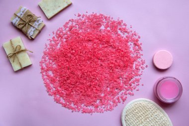 Dairenin içine tuz döküldü, doğal sabun, duş süngeri, banyo bombası, pembe arka planda krema. Rahatlama, vücut bakımı, organik banyo ürünleri. Spa kozmetik. Düz yatıyordu. Boşluğu kopyala.