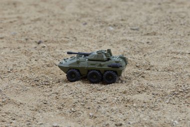 Kumsaldaki yeşil oyuncak bir askeri araca yakından bakın.