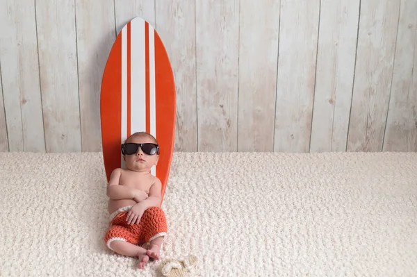Yeni doğan bebek çocuk üzerinde sörf tahtası yaslanmış — Stok fotoğraf
