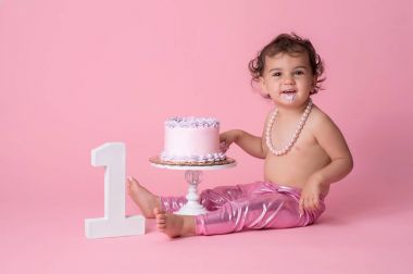 Bir yaşındaki kız bebek doğum günü pastası ile gülümseyen