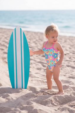 Surfboard ile plajda bir yaşındaki kız
