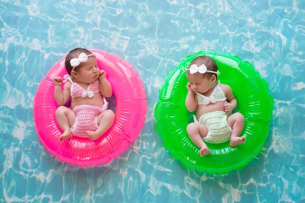 Bébé jumeaux filles flottant sur anneaux de natation — Photo