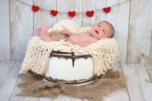 Bébé garçon dans un seau avec guirlande de coeur — Photo