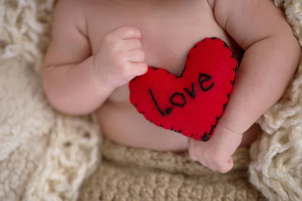 Bebê segurando um travesseiro em forma de coração — Fotografia de Stock