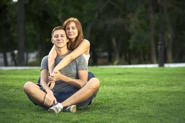 Love couple sitting on the grass in the park — Stock Photo, Image