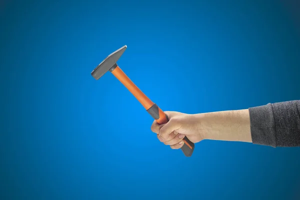 Mano del hombre sosteniendo un martillo sobre un fondo liso — Foto de Stock