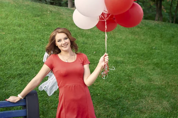 Gelukkige vrouw met ballonnen in het park — Stockfoto