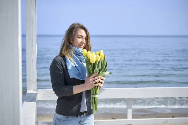 Счастливая женщина с цветами у берега моря — стоковое фото