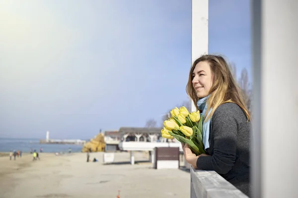 Femme heureuse avec des fleurs près du bord de la mer — Photo