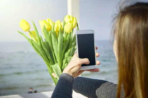 Jeune femme avec des fleurs faisant selfie — Photo