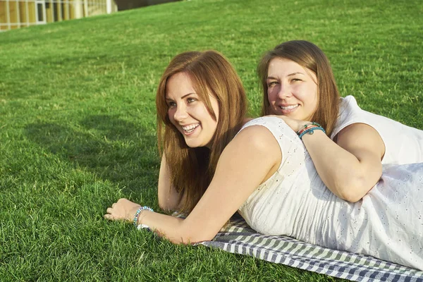 Twee vriendinnen liggen op het gazon — Stockfoto