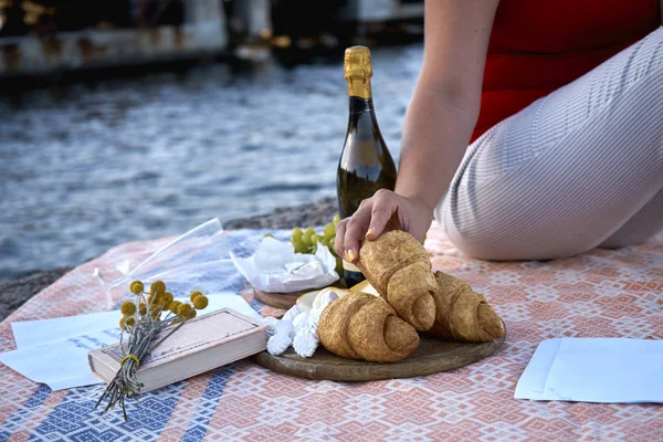 Donna che prende gustoso e fresco croissant seduto vicino al mare — Foto Stock