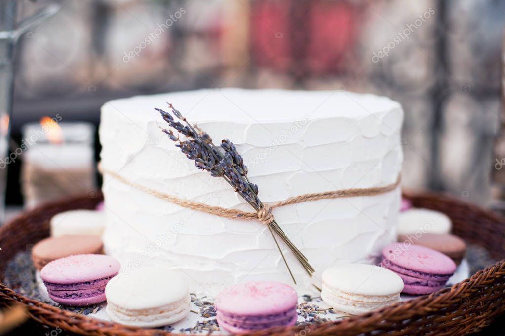 white cake with cream, macaroons and lavender flowers