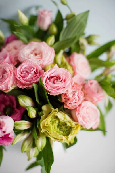 Gül desenli parlak buket, beyaz vazoda östoma ve alstromerya. Yumuşak mavi arkaplanda bir buket