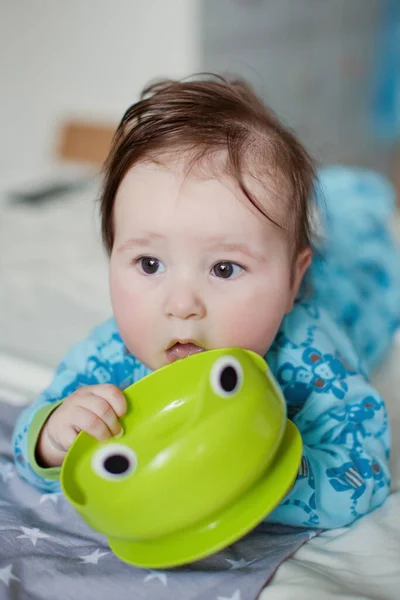 赤ちゃん男の子遊びともに彼の緑のプラスチックプレート — ストック写真