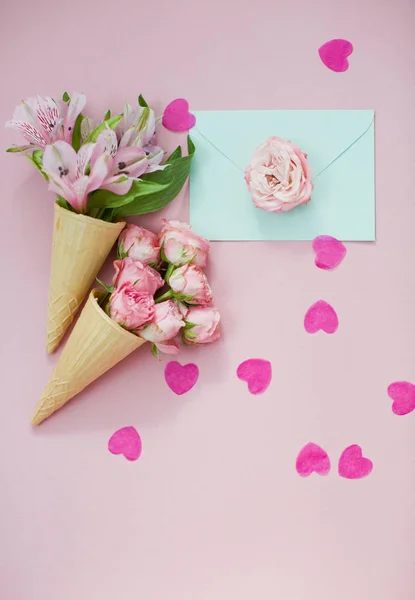 冰淇淋锥与粉红色的花和薄荷信封粉红色的面糊背景与心形圆饼 顶部视图 — 图库照片