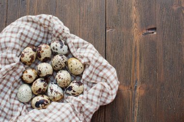Kareli kahverengi peçete ve ahşap arka planda bıldırcın yumurtası yığını