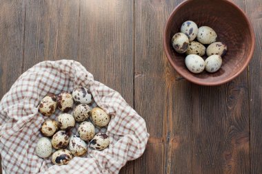Ahşap bir arka planda kil kahverengi bir kasede bıldırcın yumurtası.