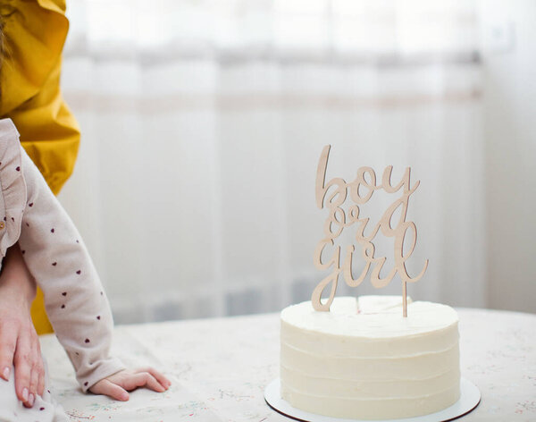 White "Boy or girl" cake for gender reveal party with wooden topper