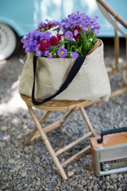 Tahta koltukta pembe ve mor çiçekli çuval bezi.