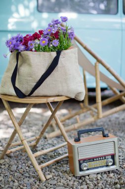 Tahta koltukta pembe ve mor çiçekli çuval bezi.